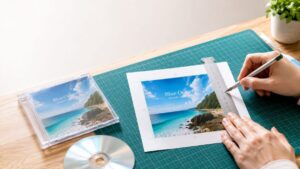 定規とカッターを使ってCDジャケットをきれいに切り抜いている画像